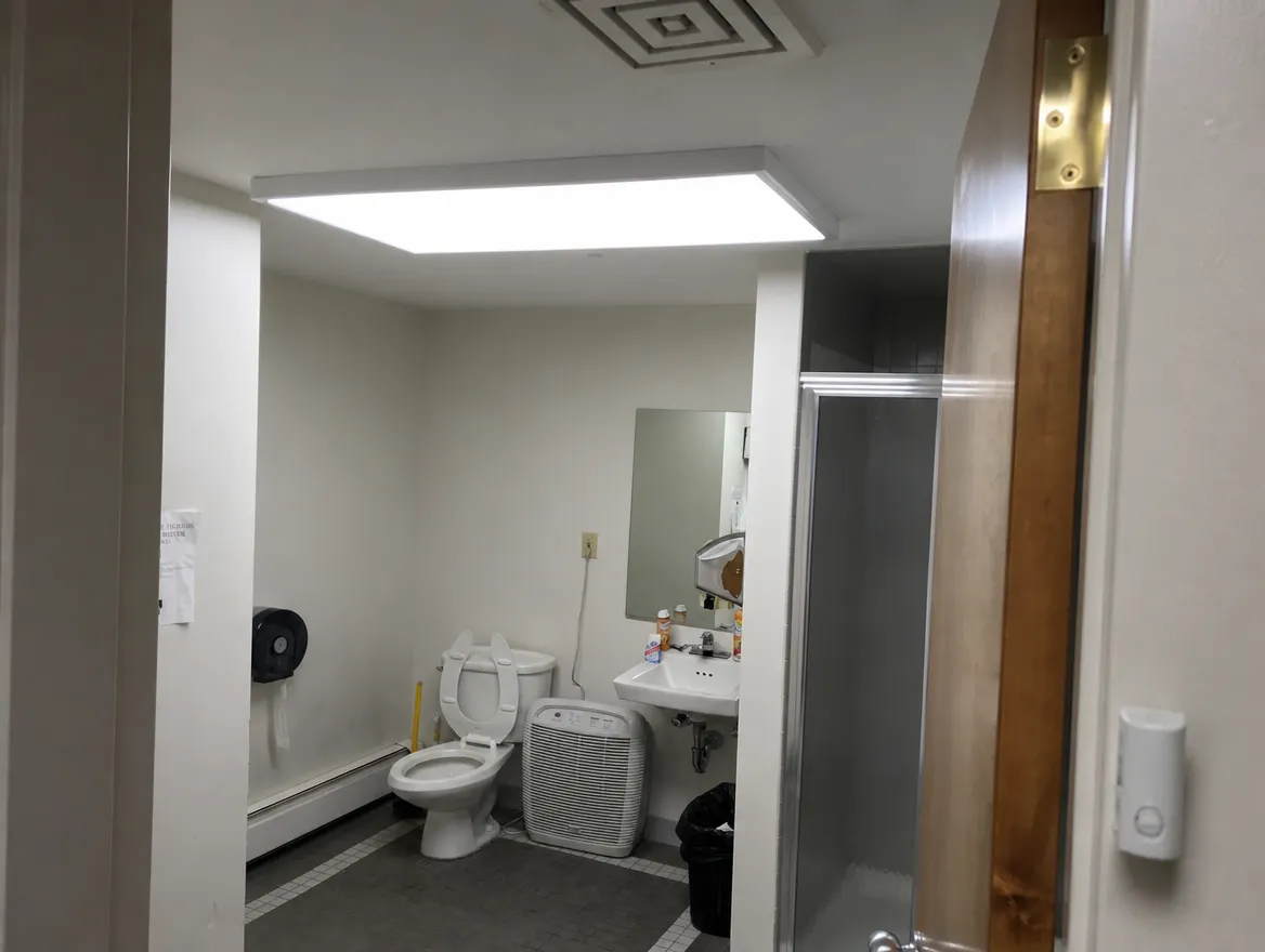 A small commercial restroom with a ceiling panel light